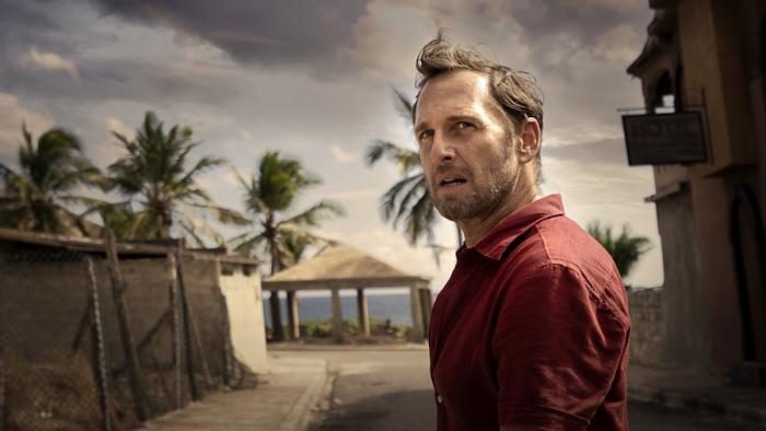 The Black Demon Movie: Oil company inspector Paul Sturges (Josh Lucas), standing in a run-down beachside resort town, looks warily over his shoulder