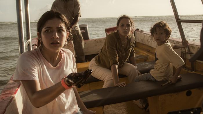 The Black Demon Movie: Audrey, Ines, and Tommy are in a small boat looking alarmed as Audrey has oil smeared on her hand