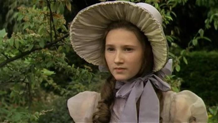 The Amazing Mr. Blunden: A young White girl stands wearing a large bonnet in a garden