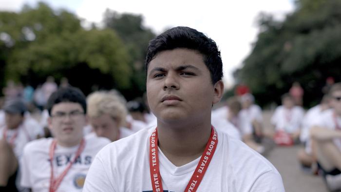 Boys State Movie: Steven Garza in foreground among group of boys in white T-shirts wearing red "Texas Boys State" lanyards