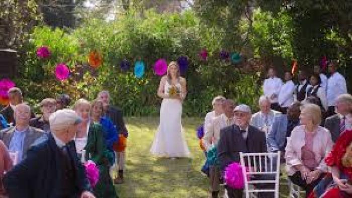Bride of the Year: Bride walking down an outdoor aisle, guests seated, with colorful decorations.