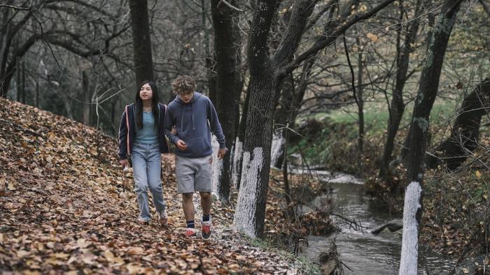Bring Her Back Movie: Piper (Sora Wong) holds her half-sibling Andy's (Billy Barratt) arm as they walk through the woods