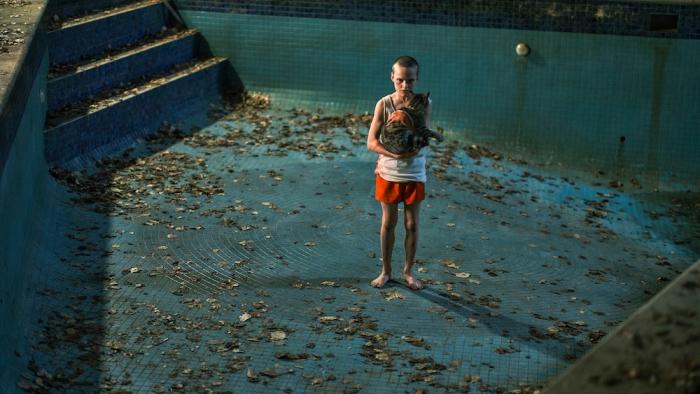 Bring Her Back Movie: Oliver (Jonah Wren Phillips) stands in an empty swimming pool, menacingly holding a cat