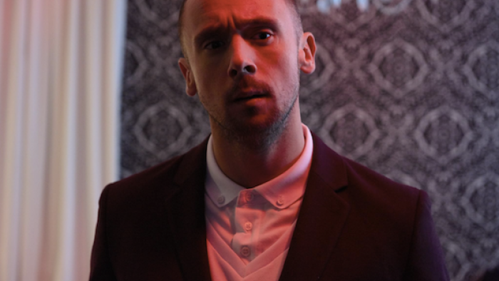Brotherhood: A young White man looks serious wearing a suit inside a fancy London home