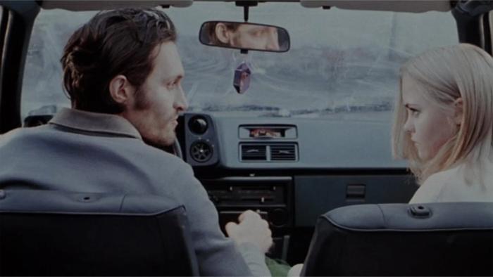 Buffalo '66: A man and woman sit facing each other in the front seats of a car with serious expressions on their faces