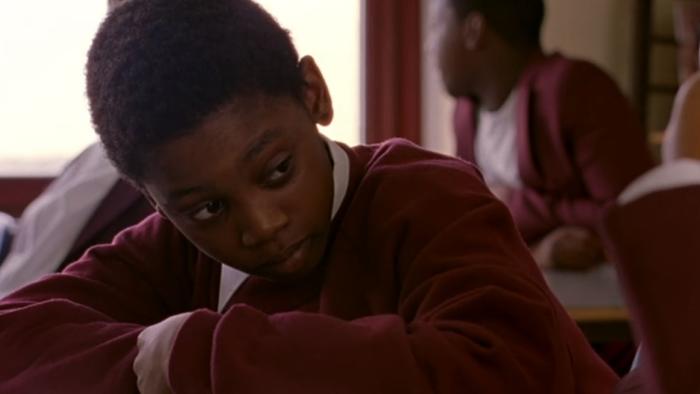Bullet Boy: Luke Fraser sits at school desk looking to one side while wearing a red sweatshirt and white shirt