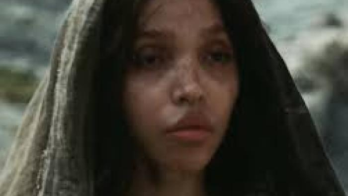 The Carpenter's Son Movie: The Mother (FKA Twigs) wears a scarf on her head and looks into the distance