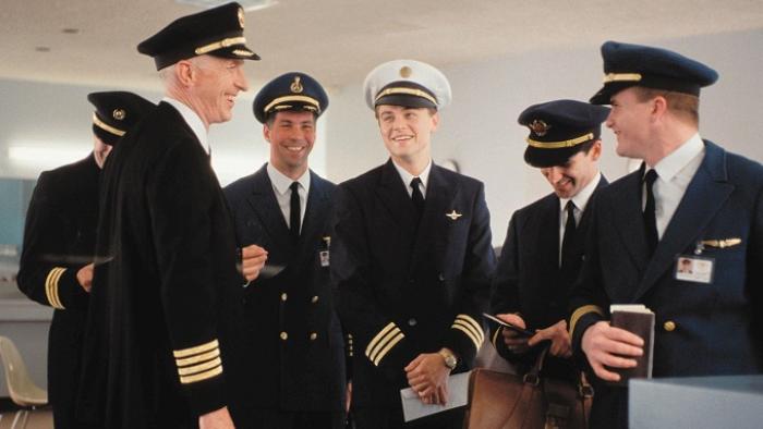 Catch Me If You Can movie: Frank, dressed as a pilot, smiles in a group of older pilots in an airport