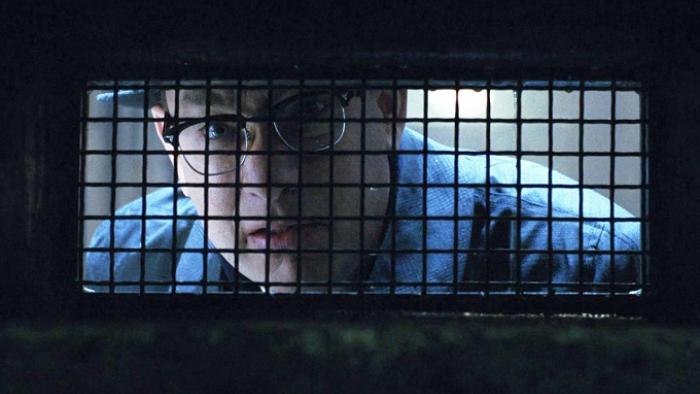 Catch Me If You Can movie: Carl peers through a grille into a dark solitary room at a French prison