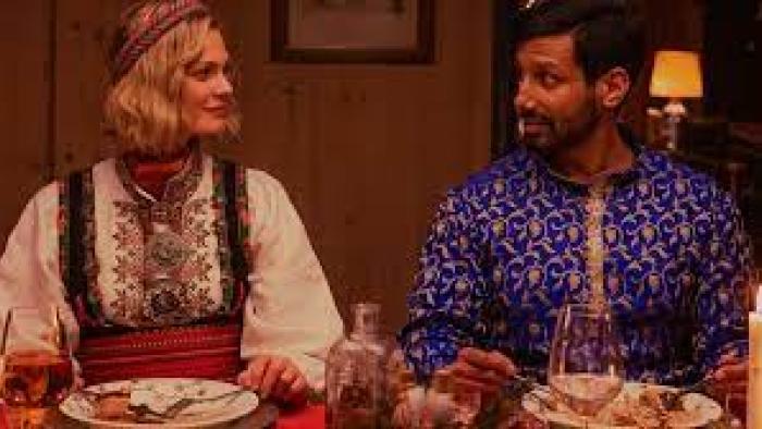 Christmas as Usual scene 2: White woman and Indian man eat in native dress