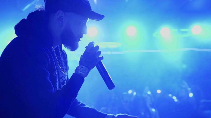 Clika Movie: Bathed in blue light, Chito holds a microphone and performs for his fans
