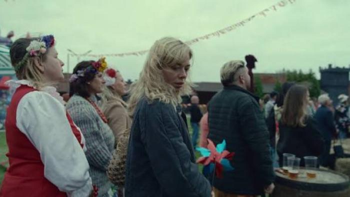 Colors of Evil: Black: Crowd at an outdoor festival; a woman looks back, holding a windmill toy.