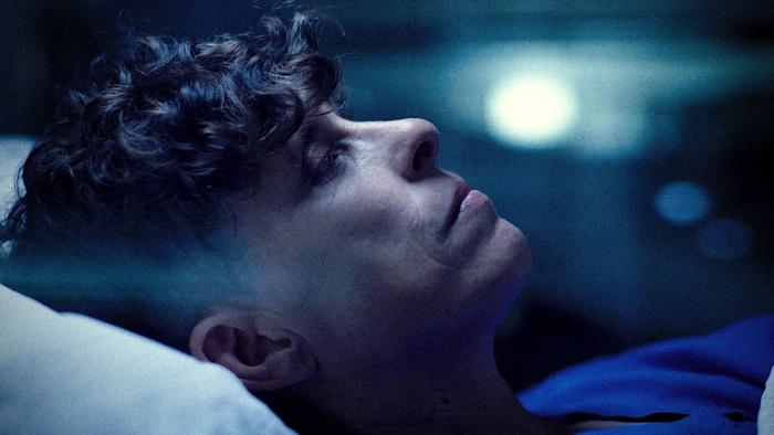 Come See Me in the Good Light movie: Andrea Gibson lies on a bed, their face profile to the audience