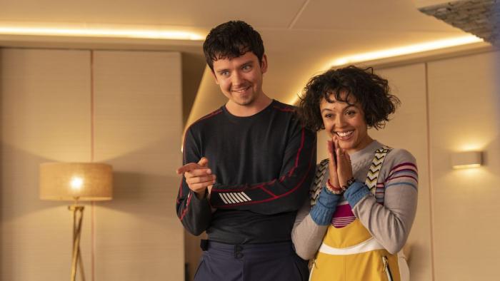 Your Christmas or Mine 2: A young White man and a young biracial woman smile and point toward someone out of shot.