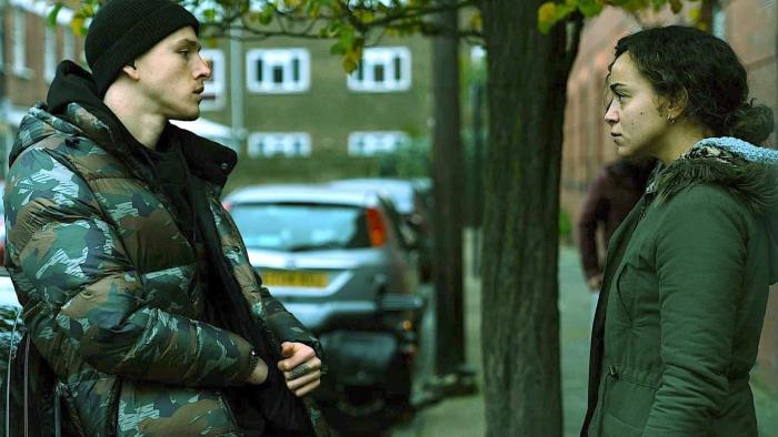 County Lines: A young man and a mother stand facing each other in the street, looking serious