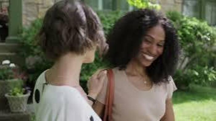 Dancing with a Murderer: Two women smiling and chatting outside in a garden area.