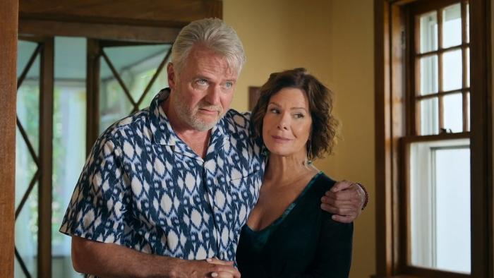 Daughter of the Bride Movie: A grey-haired man in a colorful print shirt holds has one arm around a woman's shoulder, holding her close while holding 