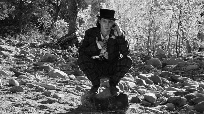 Dead Man: Johnny Depp wears a suit and cowboy hat as he crouches down in the forest, looking confused