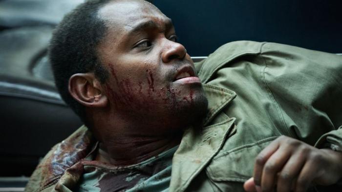 Dead Shot: A young Black man in army uniform with blood on his face looks to the right