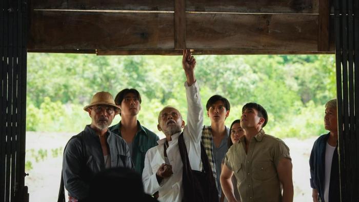 Death Whisperer movie: Thai men and a Thai woman stand under large doorway looking up at something