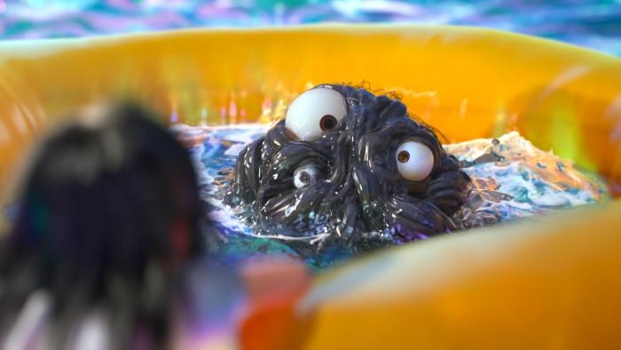 Deep Sea Movie: A black, goopy creature with eyeballs sits in the middle of a yellow life jacket