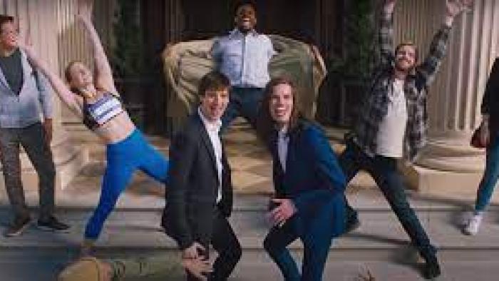 Dicks: The Musical: People in the city are dancing with two White Millennial men in the center of it all