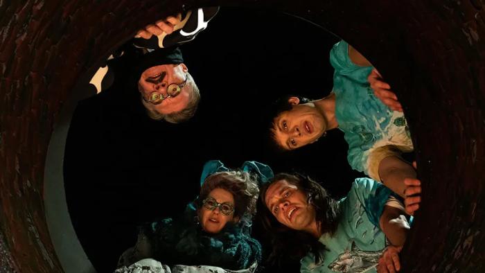 Dicks: The Musical: Two young men, an older man, and an older woman look down into a sewer