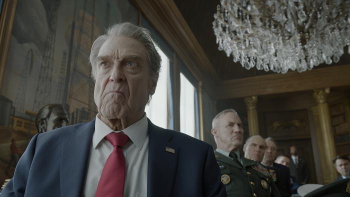 Digger movie: President Compson (John Goodman) looks angry while General Fitzgerald (Robert John Burke) stands with his cabinet behind him
