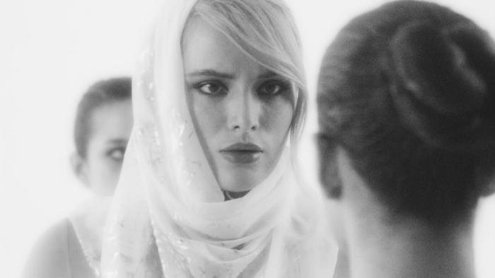 Divinity Movie: Her head wrapped in a white scarf and a concerned look on her face, Ziva speaks to a woman 