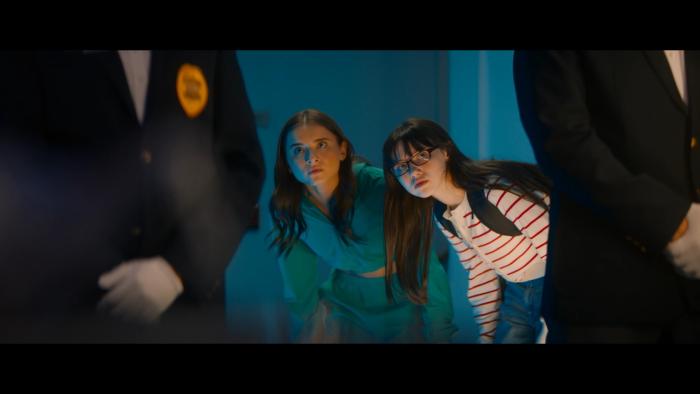 Double Trouble movie: Madeleine and Violet McGraw are crouched looking around a corner at a security guard in a hallway