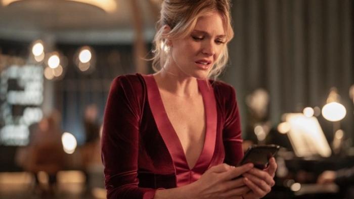 Drop Movie: Violet (Meghann Fahy), wearing a fancy red dress, looks alarmed at something on her phone