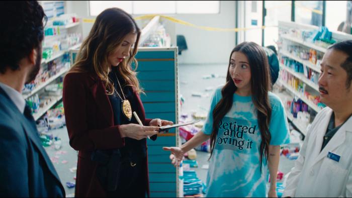 Drugstore June Movie: Police detectives speak to a young woman while a pharmacist looks on