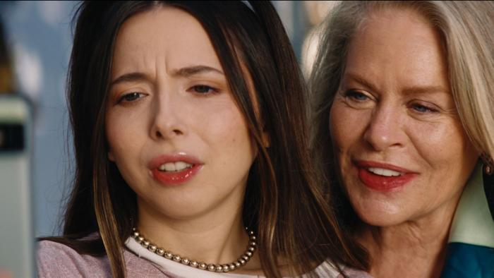 Drugstore June Movie: June is looking into her phone while her mother smiles over her shoulder