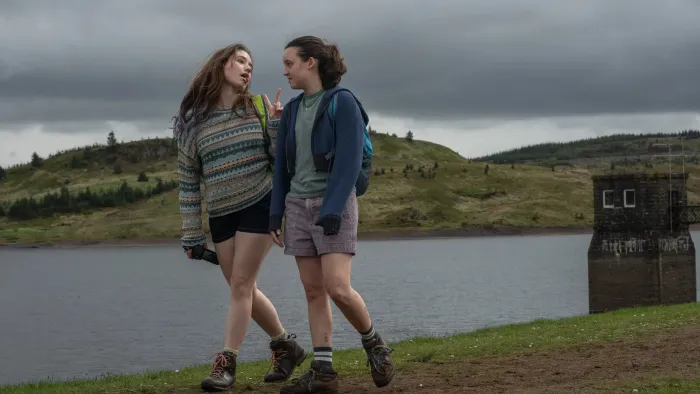 Sunny Dancer: Two teen girls walking by a lake on a cloudy day, wearing casual outdoor clothing