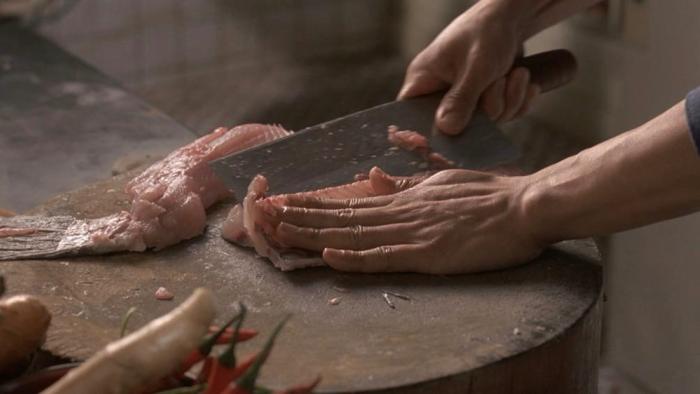 Eat Drink Man Woman movie: hands prepare to fillet a fish on a cutting board