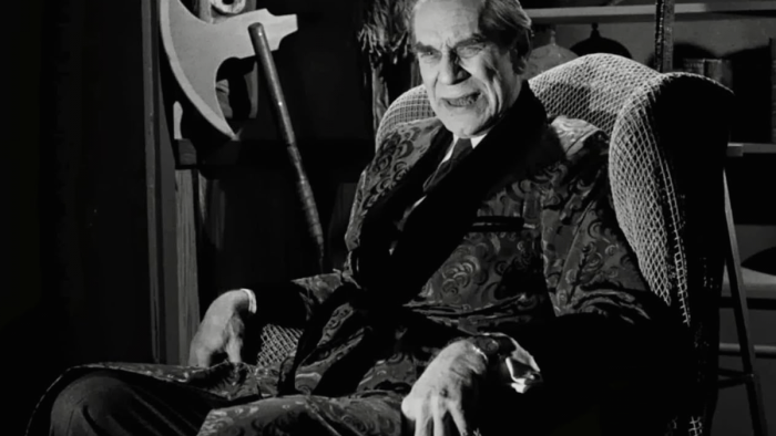Ed Wood movie: A wrinkled man in a smoking jacket sits in an armchair, halberd visible in background