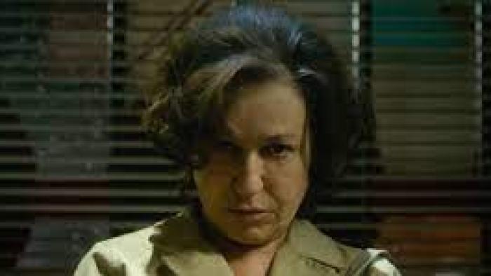 Elena Knows scene 2: Older woman looks unhappy  as the shades are closed behind her