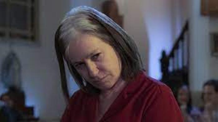 Elena Knows scene 1: Woman with gray hair looks down