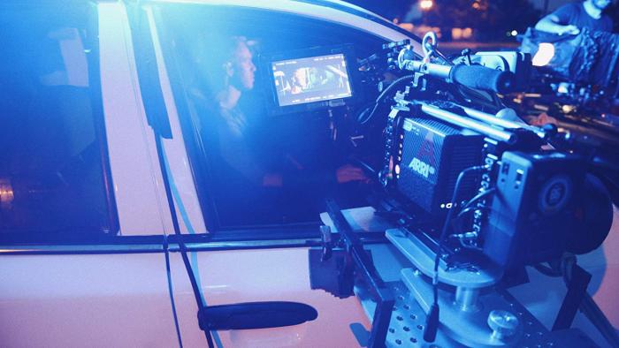 Emanuel Movie: Dylann Roof sits in a police car, looking away from a giant camera