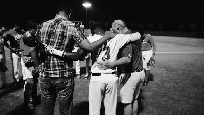 Emanuel Movie: Three men bow their heads in grief on a football field
