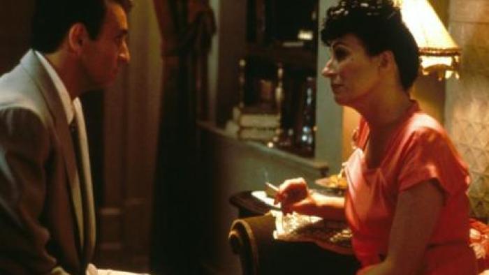 Enemies, a Love Story: A married couple argue while sitting on a bed