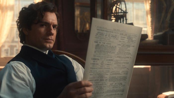 Enola Holmes 3: Henry Cavill reads a paper as Sherlock Holmes.
