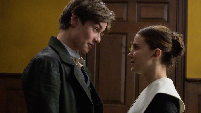 Enola Holmes movie: Lord Tewkesbury looks down at Enola who smiles back, both in a hallway next to a door