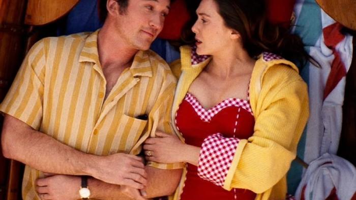 Eternity movie: Elizabeth Olsen looks concerned while Miles Teller confidently smiles back at her as they cuddle on the bottom of a rowboat