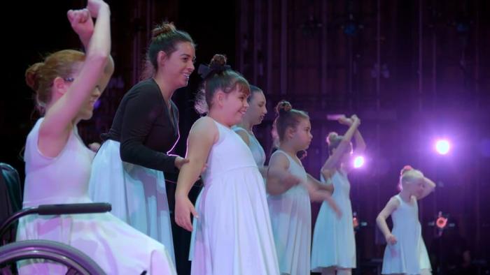 A row of dancers on stage are ready to take a bow.