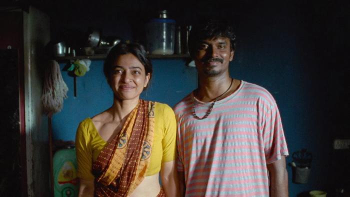 Sister Midnight: An Indian woman and man stand side by side smiling