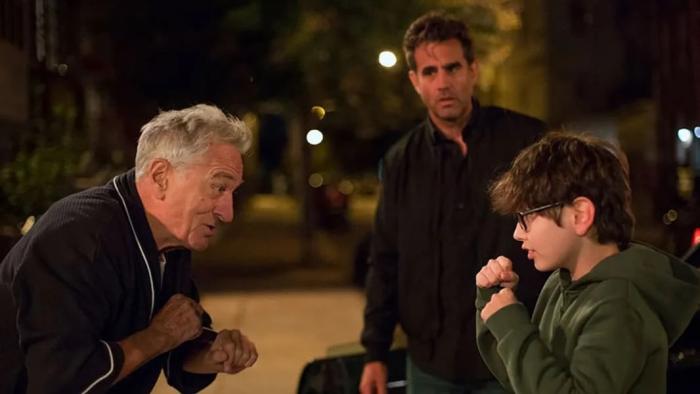 Ezra Movie: Stan and Ezra stand across from each other with their fists raised in jest, with Max in the background