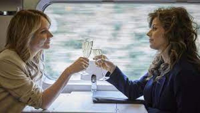 Faithfully Yours: Two women clink champagne glasses on a train