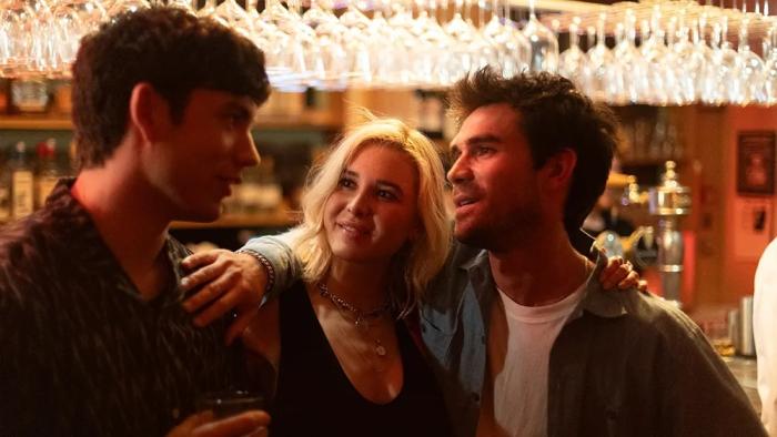 Falling movie: Three people—a couple and his best male friend—smiling at a bar, with warm lighting and glasses overhead