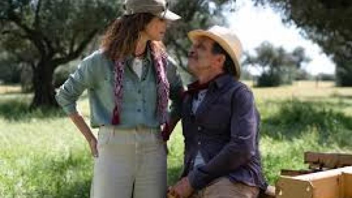 Familia scene 3: A woman stands and talks to a man sitting down